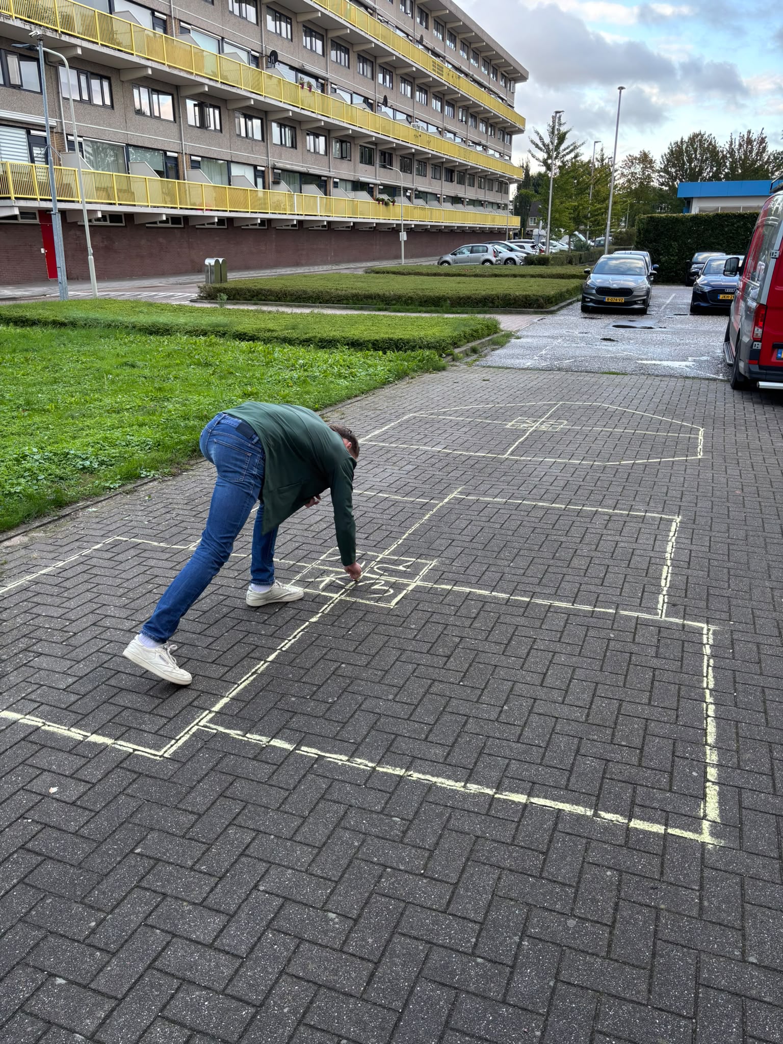 Een spelvak wordt met stoepkrijt op de bestrating getekend